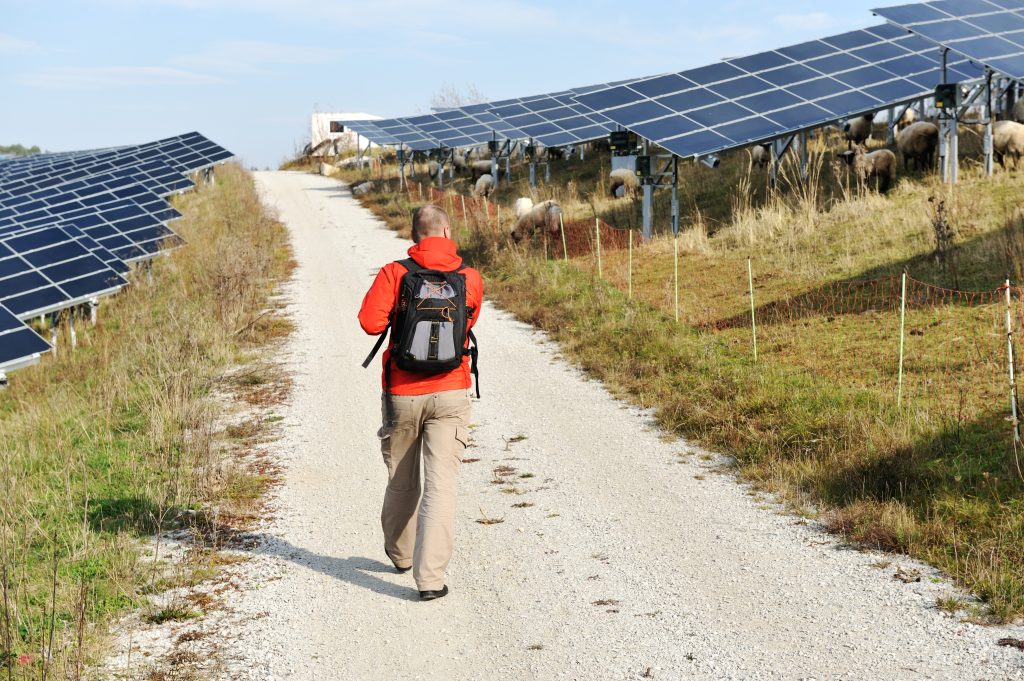 man walking on a countryside road with solar panels BYSI2jpri